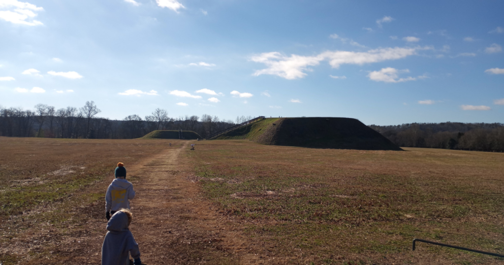 two children running towards a native burial mound at Etowah