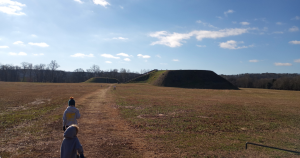 two children running towards a native burial mound at Etowah